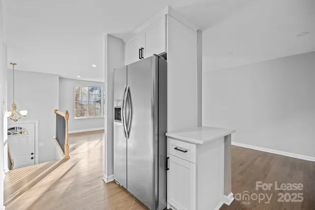a view of a refrigerator in kitchen and an empty room