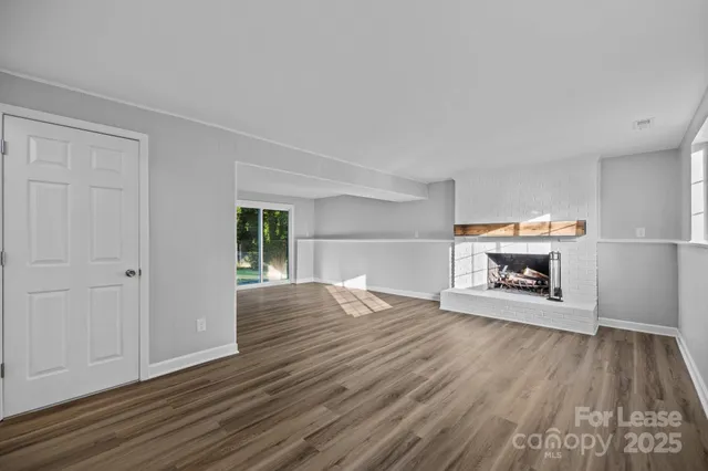a view of empty room with wooden floor and fireplace