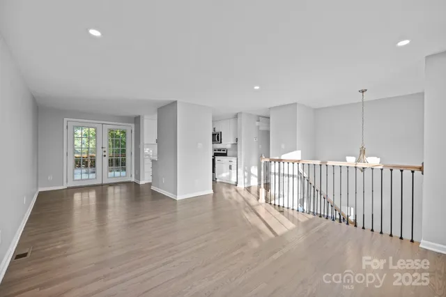 a view of an empty room with wooden floor and windows
