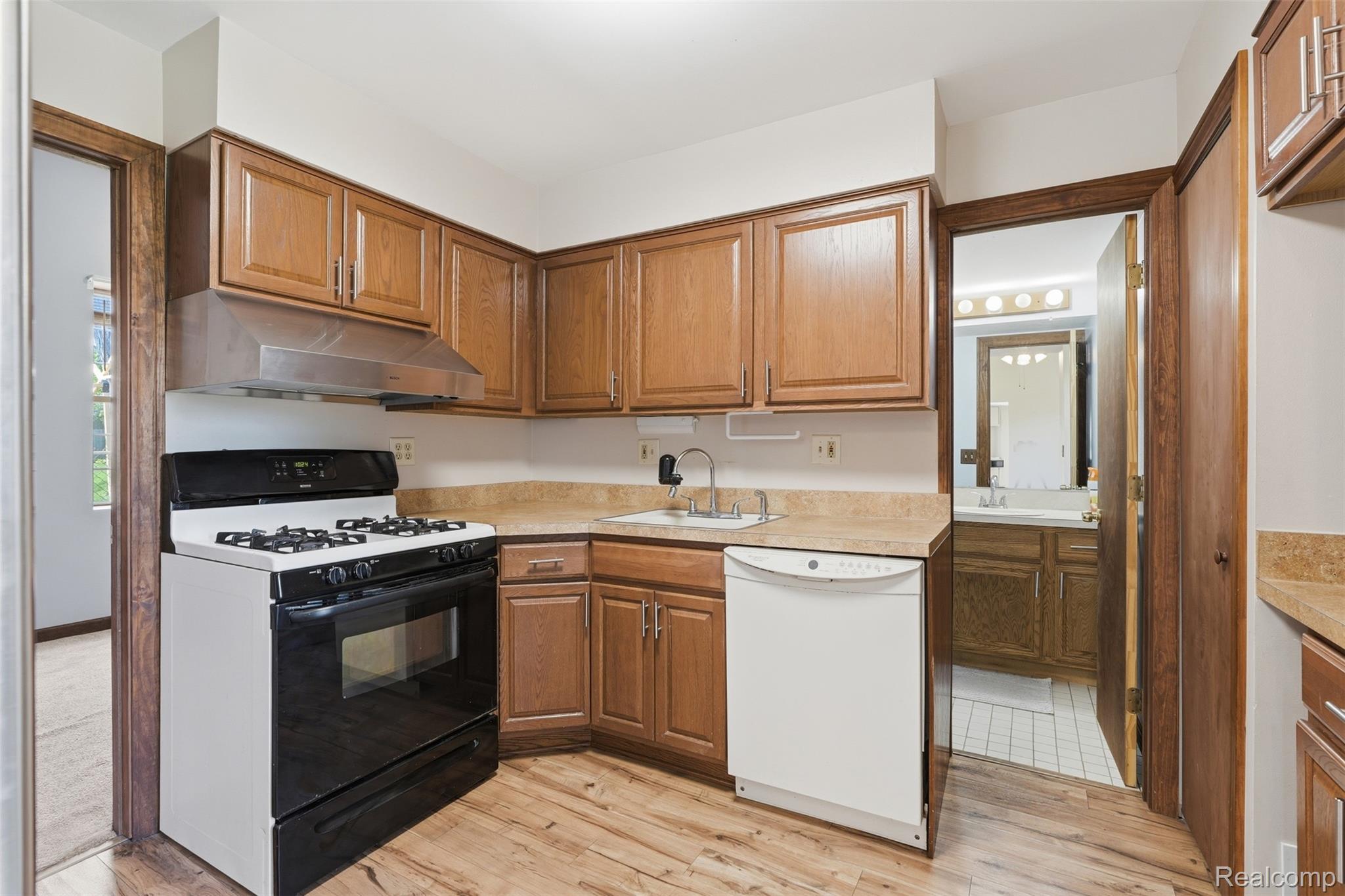 5634 Chicago Road Warren, MI 48092 - Photo 9 of 36 Kitchen featuring wood-finish flooring, oak cabinetry, stainless steel range hood, sink, and a white dishwasher