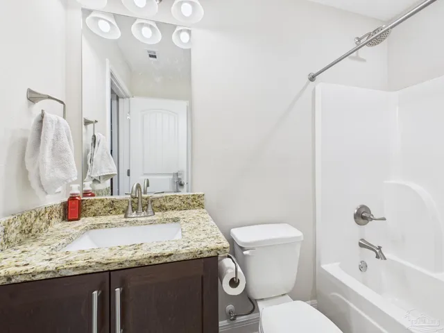 a bathroom with a granite countertop sink a mirror and a toilet