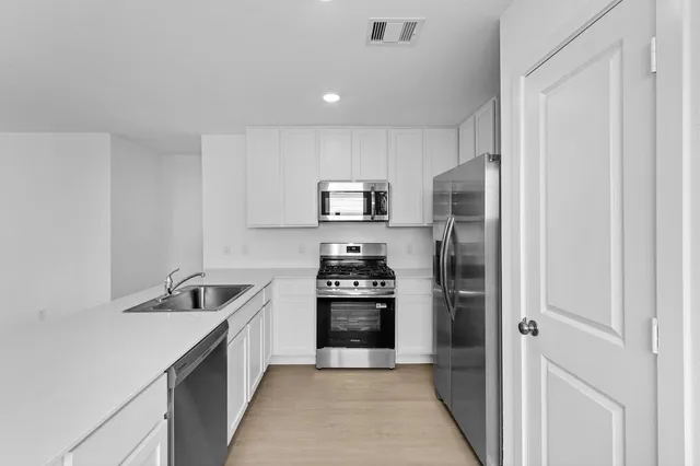 a kitchen with a sink a counter top space cabinets and stainless steel appliances