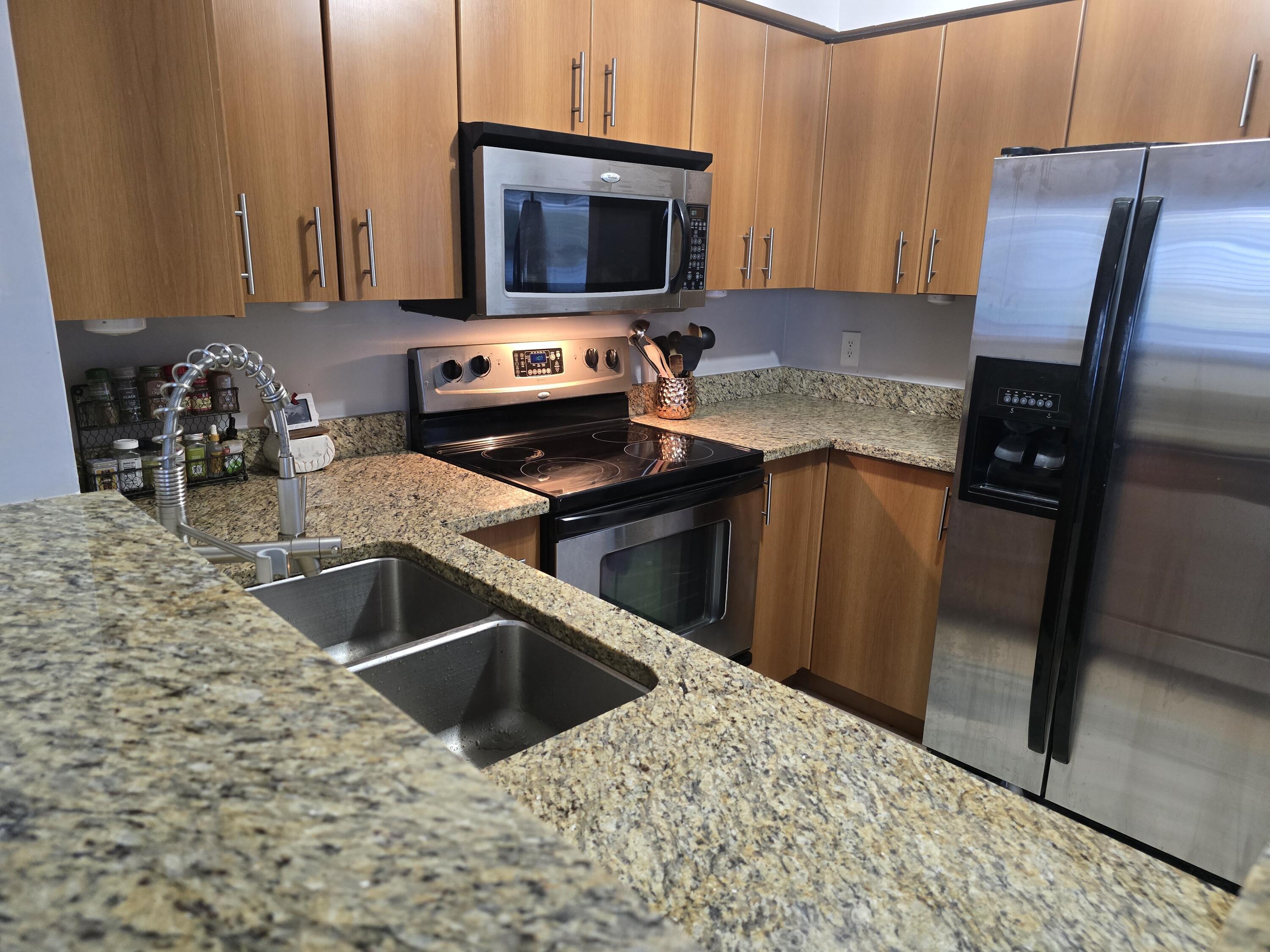 a kitchen with stainless steel appliances kitchen island granite countertop a sink a stove and a microwave with wooden floor
