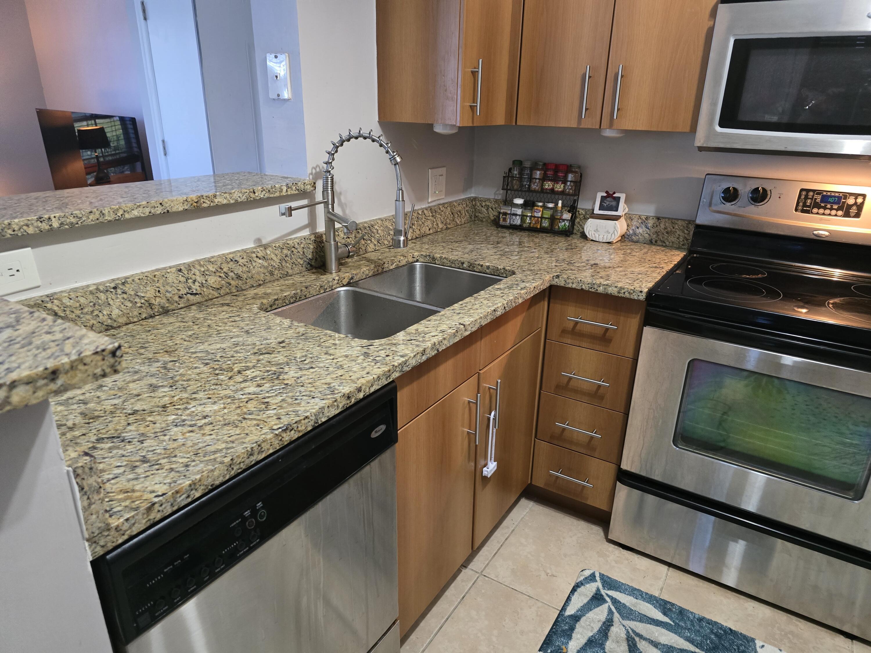 1215 Crystal Way, Unit O Delray Beach, FL 33444 - Photo 3 of 14 a kitchen with granite countertop a sink stove and cabinets