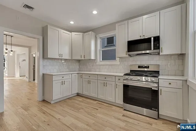 a kitchen with stainless steel appliances granite countertop a stove top oven a sink and white cabinets