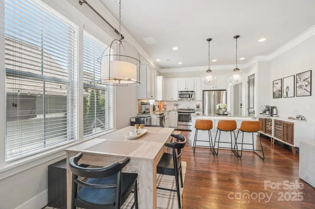 a kitchen with stainless steel appliances granite countertop a stove refrigerator a sink dishwasher a dining table and chairs with wooden floor