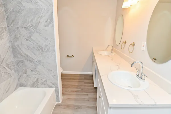 a bathroom with a tub sink and mirror