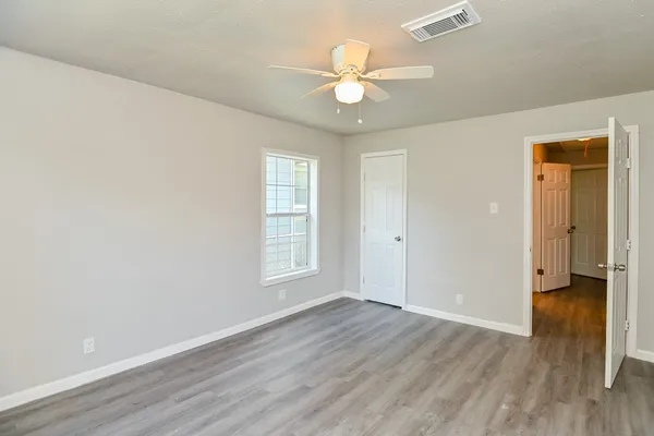 an empty room with wooden floor and windows