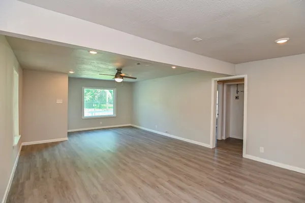 an empty room with wooden floor and windows