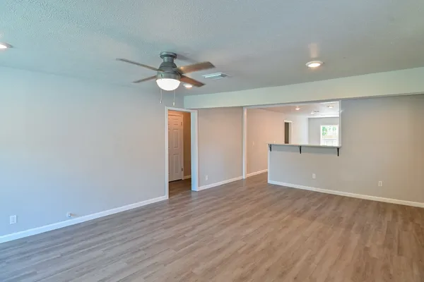 a view of an empty room with window and wooden floor