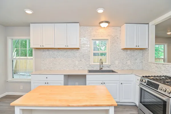 a kitchen with stainless steel appliances white cabinets and a stove top oven