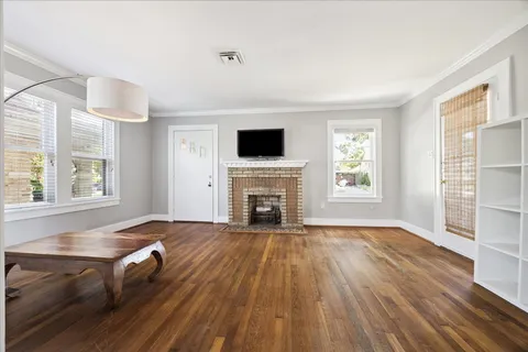 an empty room with windows fireplace and wooden floor