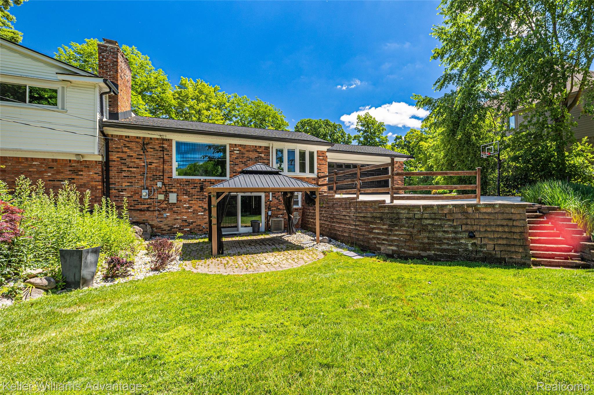 5722 Raven Road Bloomfield Hills, MI 48301 - Photo 33 of 34 Expansive backyard featuring a manicured lawn, brick exterior, and a multi-level outdoor living space