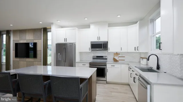 a kitchen with stainless steel appliances a sink a stove a refrigerator with white cabinets and wooden floor