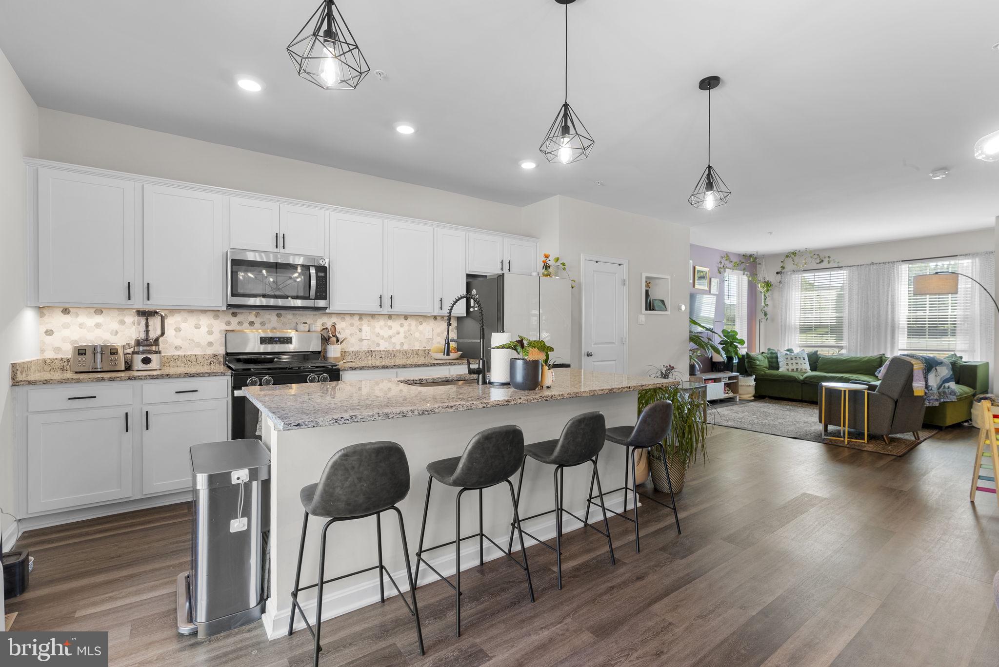 8656 Walter Martz Road Frederick, MD 21702 - Photo 11 of 30 a kitchen with stainless steel appliances granite countertop a refrigerator a stove a sink a dining table and chairs with wooden floor