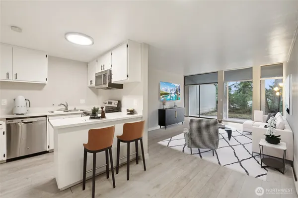 a kitchen with stainless steel appliances a white table chairs and a refrigerator