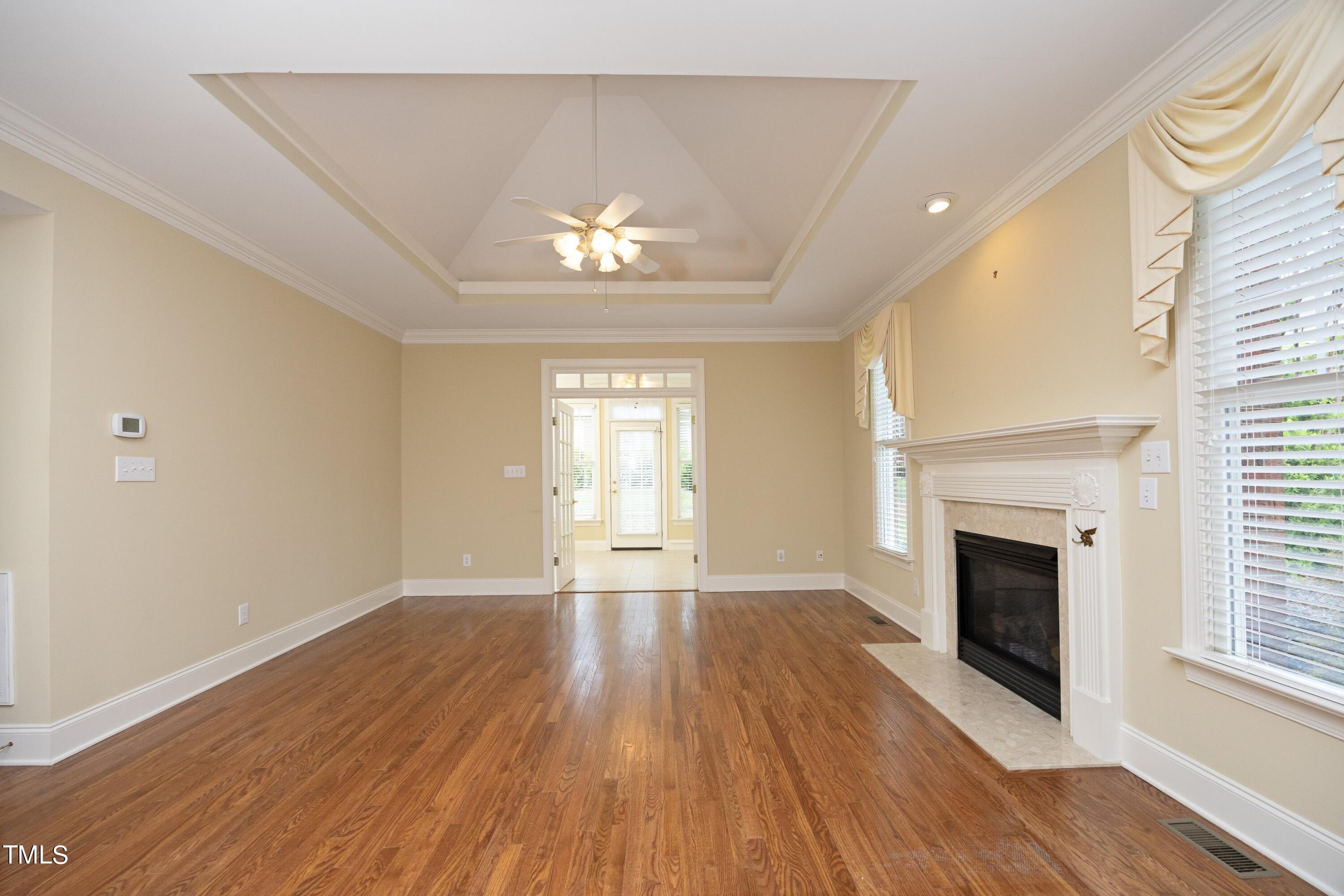 8805 Leeshire Lane Raleigh, NC 27615 - Photo 6 of 26 an empty room with wooden floor fireplace and windows
