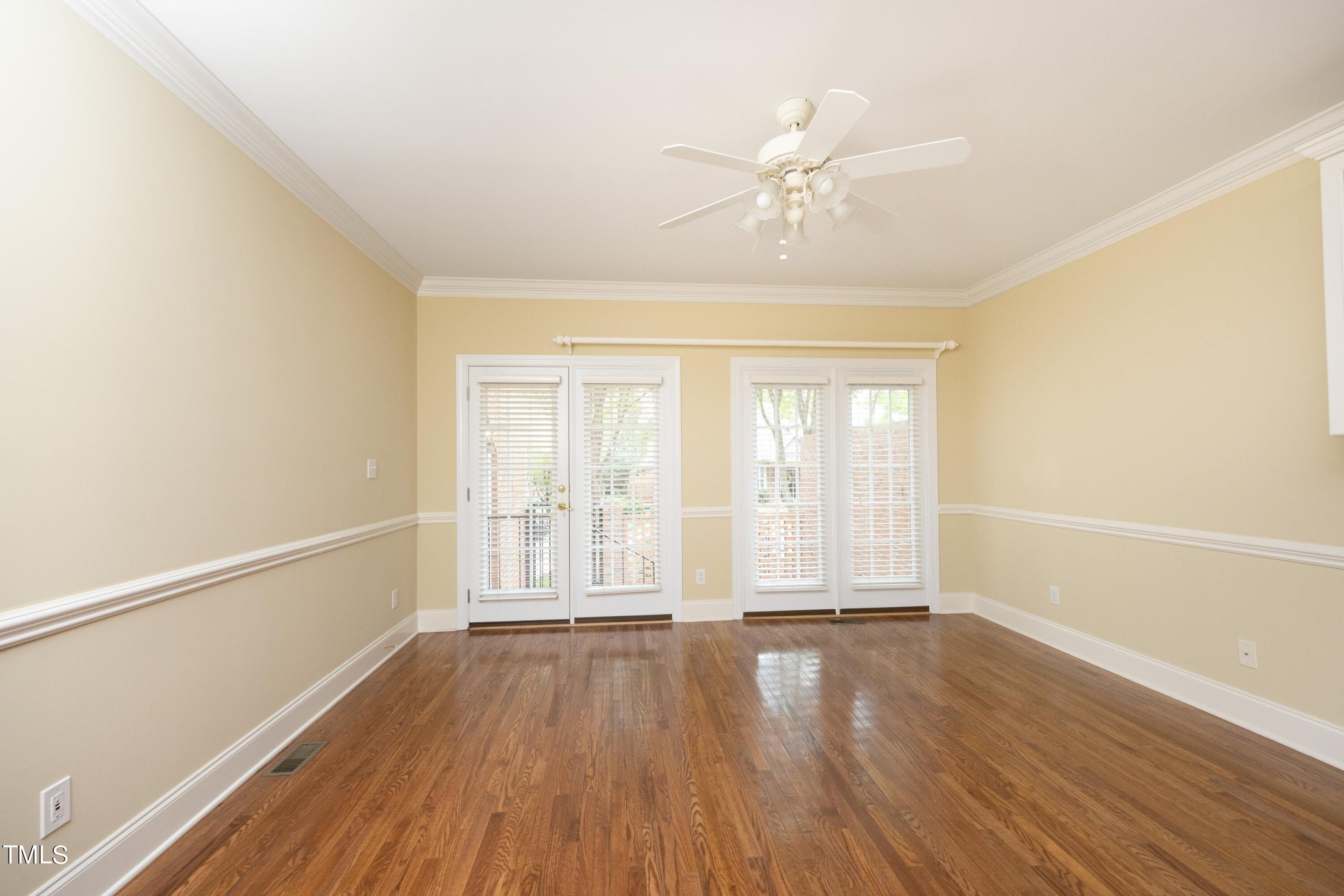 8805 Leeshire Lane Raleigh, NC 27615 - Photo 7 of 26 an empty room with wooden floor and windows with curtains