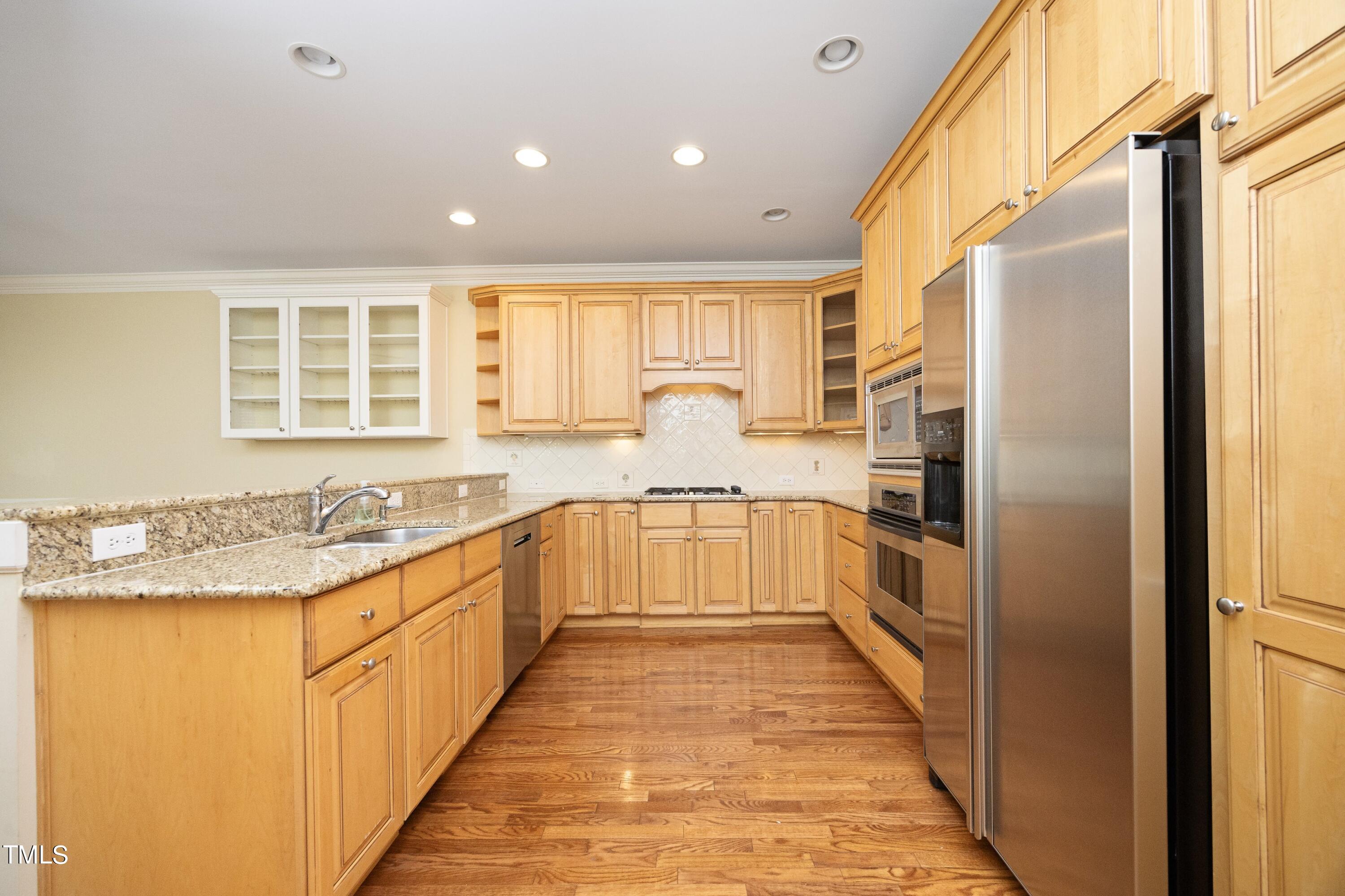 8805 Leeshire Lane Raleigh, NC 27615 - Photo 9 of 26 a large white kitchen with granite countertop a sink and dishwasher a refrigerator a oven with wooden floors
