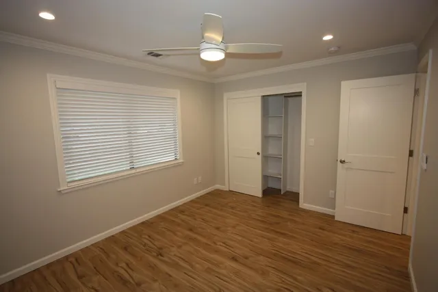 a view of an empty room with wooden floor and a window