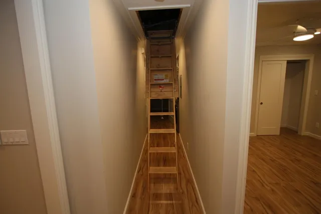 a view of a hallway with wooden floor and a bathroom