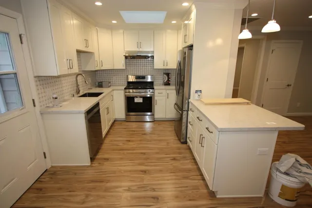 a large kitchen with a stove a sink a refrigerator and a oven