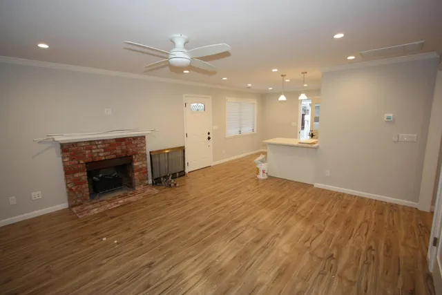 an empty room with wooden floor fireplace and windows