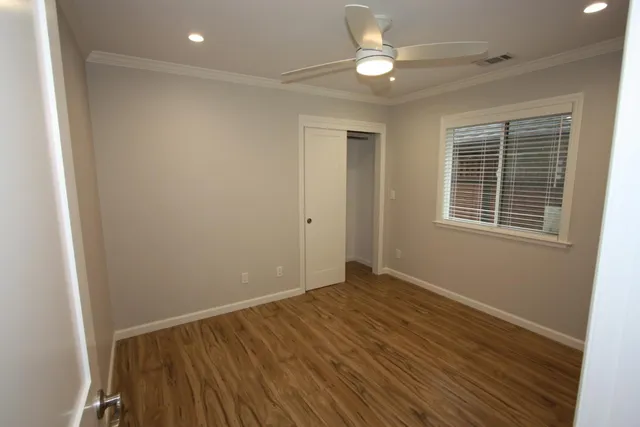 a view of an empty room with wooden floor and a window