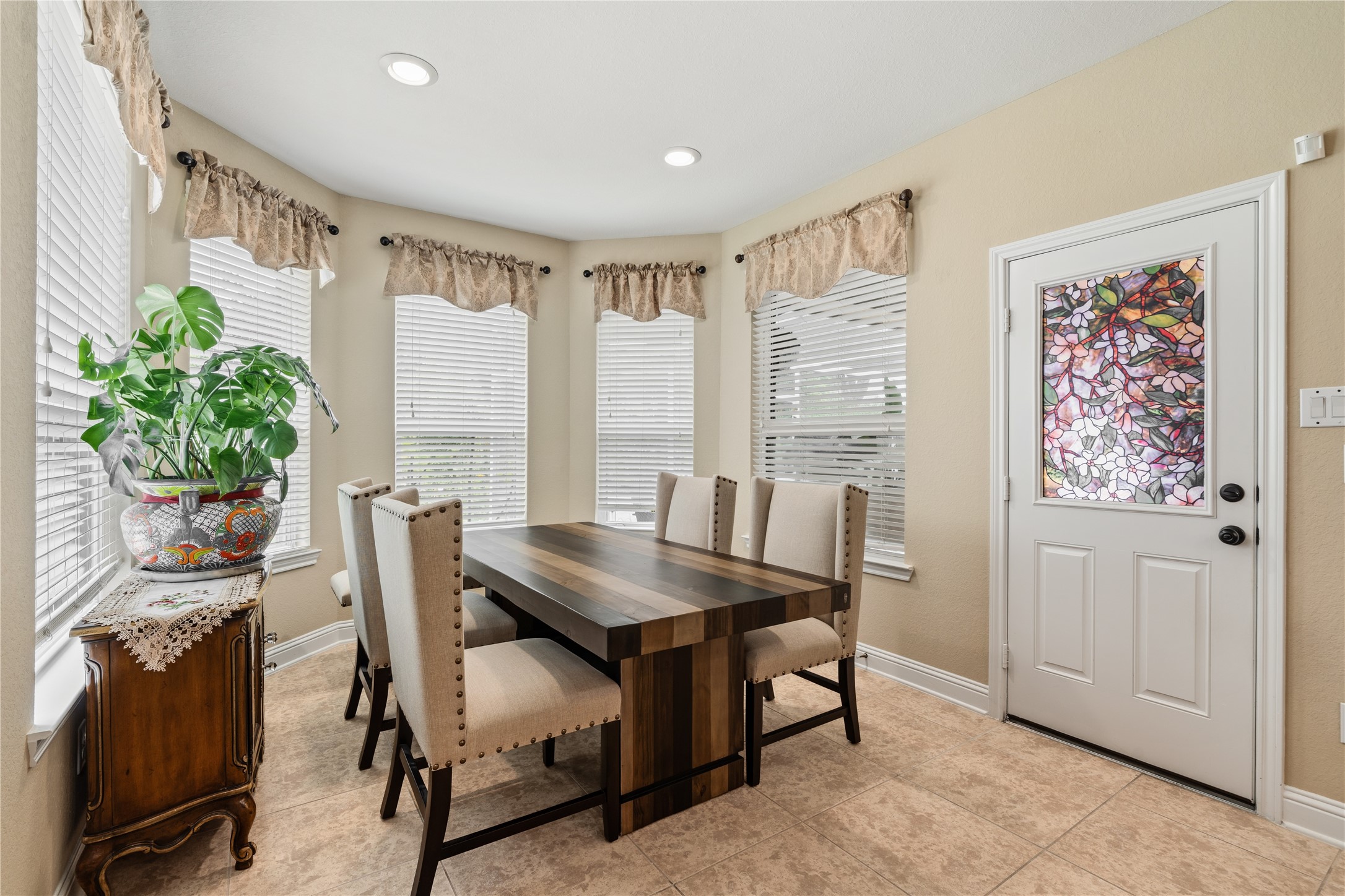 5802 Layton Meadows Lane Spring, TX 77379 - Photo 18 of 42 Breakfast nook - Bay windows, valance curtains, solid wood dining table with upholstered chairs, stained glass back door, and tile floors. Warm and charming.