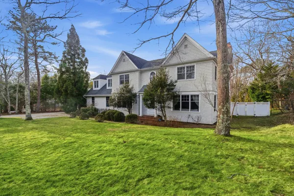 a front view of a house with a garden and trees