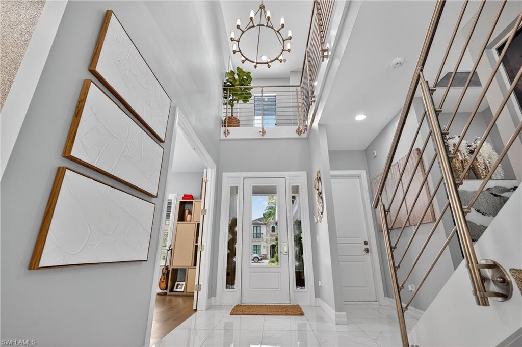 14690 Reserve Place Naples, FL 34109 - Photo 2 of 48 Foyer featuring a chandelier, light marble finish floors, and a towering ceiling