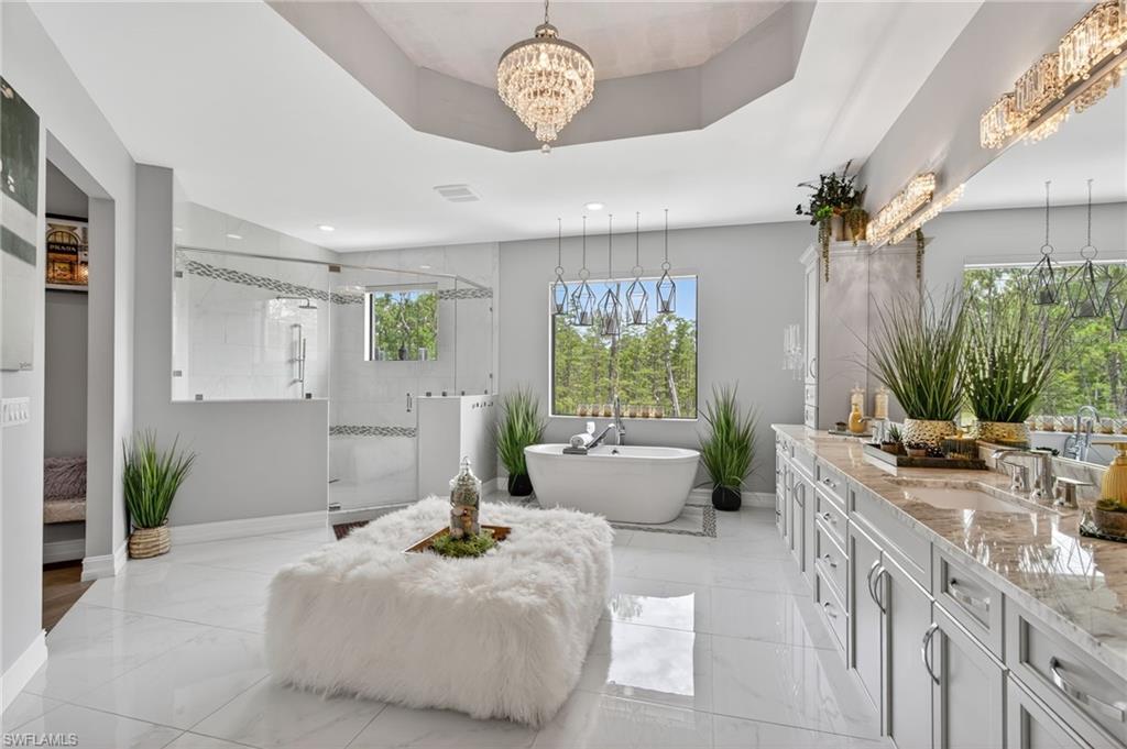 14690 Reserve Place Naples, FL 34109 - Photo 26 of 48 Bathroom with vanity, a freestanding tub, a stall shower, a tray ceiling, and a chandelier