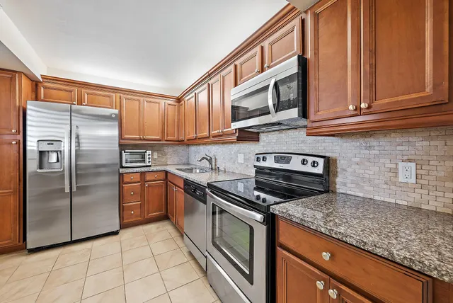 a kitchen with stainless steel appliances granite countertop a refrigerator a stove and a sink