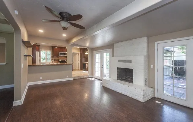 a view of an empty room with chandelier fan and a window