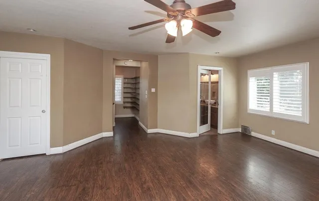 a view of empty room with wooden floor and fan