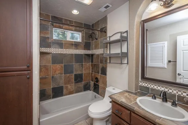 a view of a small house with wooden fence and large trees