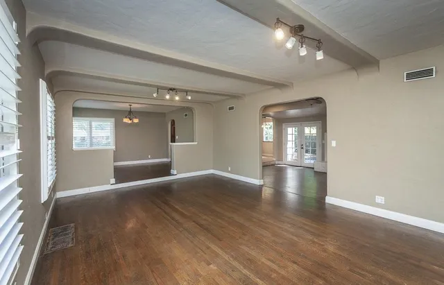 an empty room with wooden floor cabinet and windows