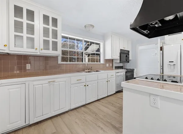 a kitchen with cabinets appliances a sink and a window