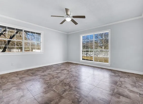 an empty room with windows and ceiling fan