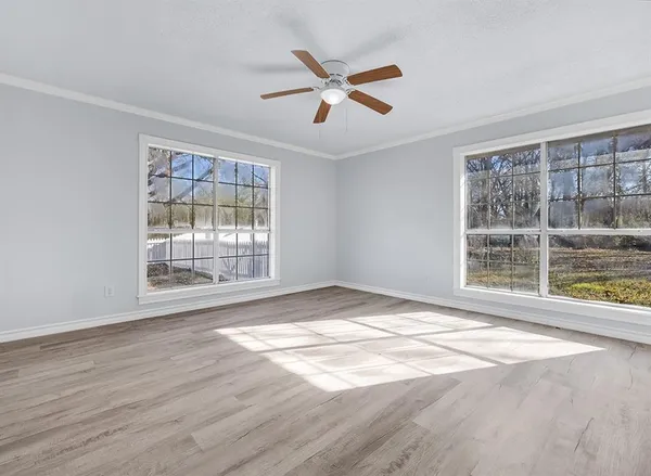 a view of an empty room with wooden floor and a window