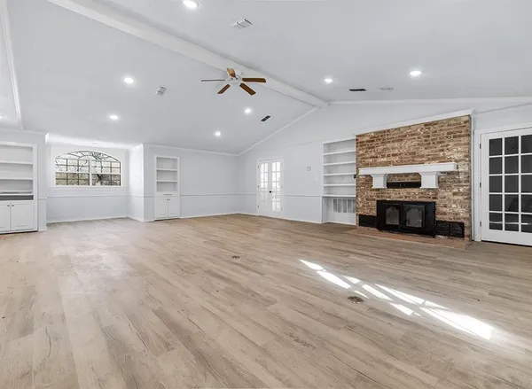 an empty room with windows and fireplace