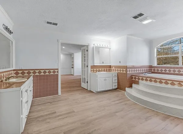 a spacious bathroom with a tub double vanity sink and a mirror