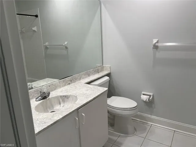 a bathroom with a granite countertop sink and a toilet