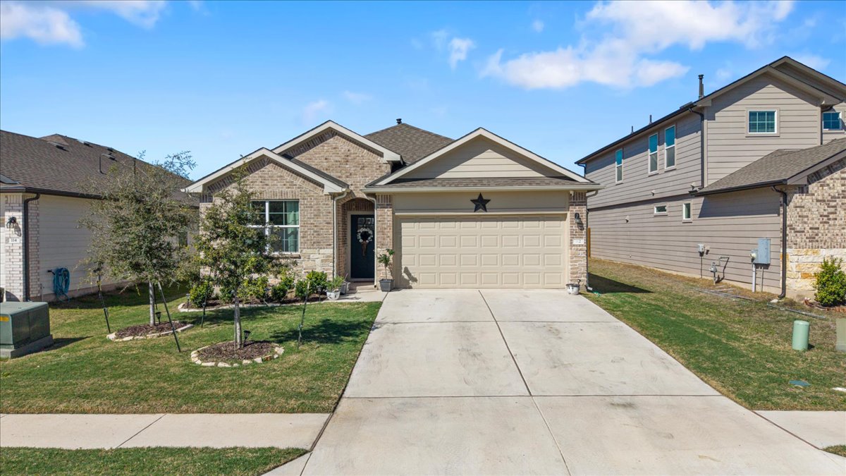 Ranch-style house with a garage, brick siding, driveway, and a front lawn