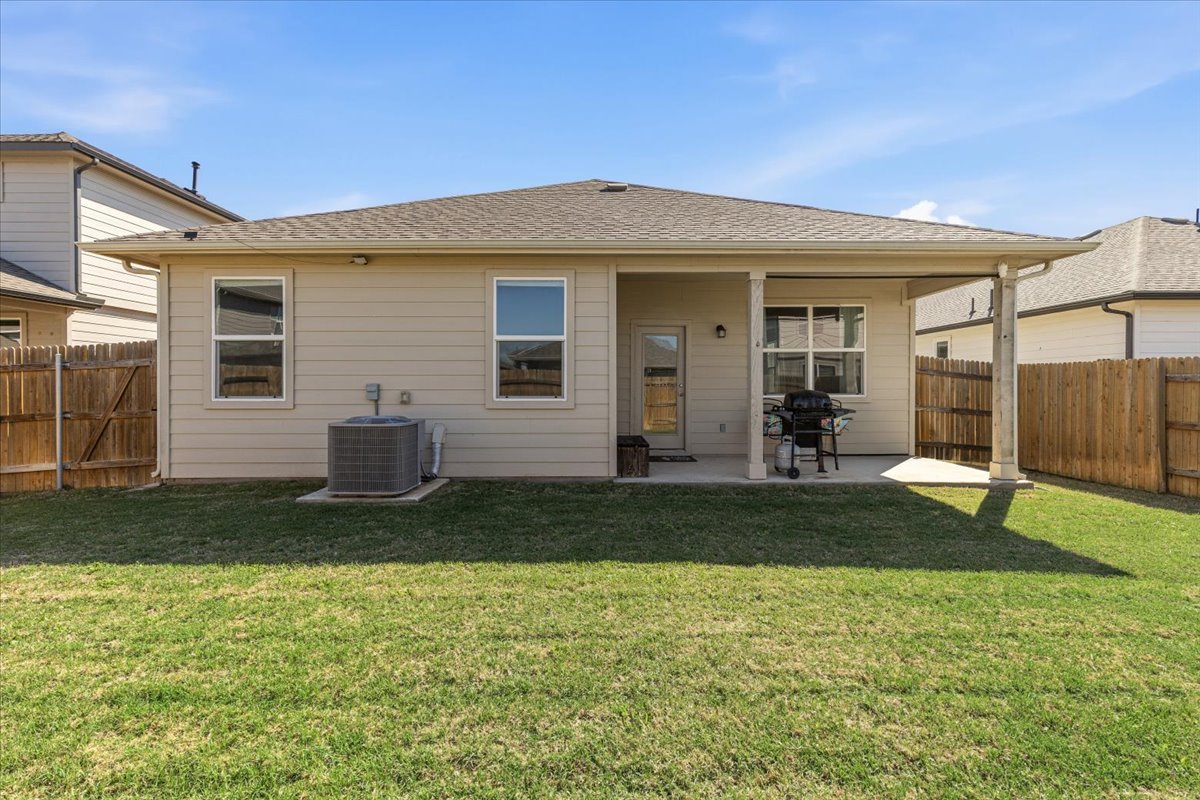 112 Rainmaker Cove Bastrop, TX 78602 - Photo 25 of 34 Back of house with a patio, a fenced backyard, and a shingled roof