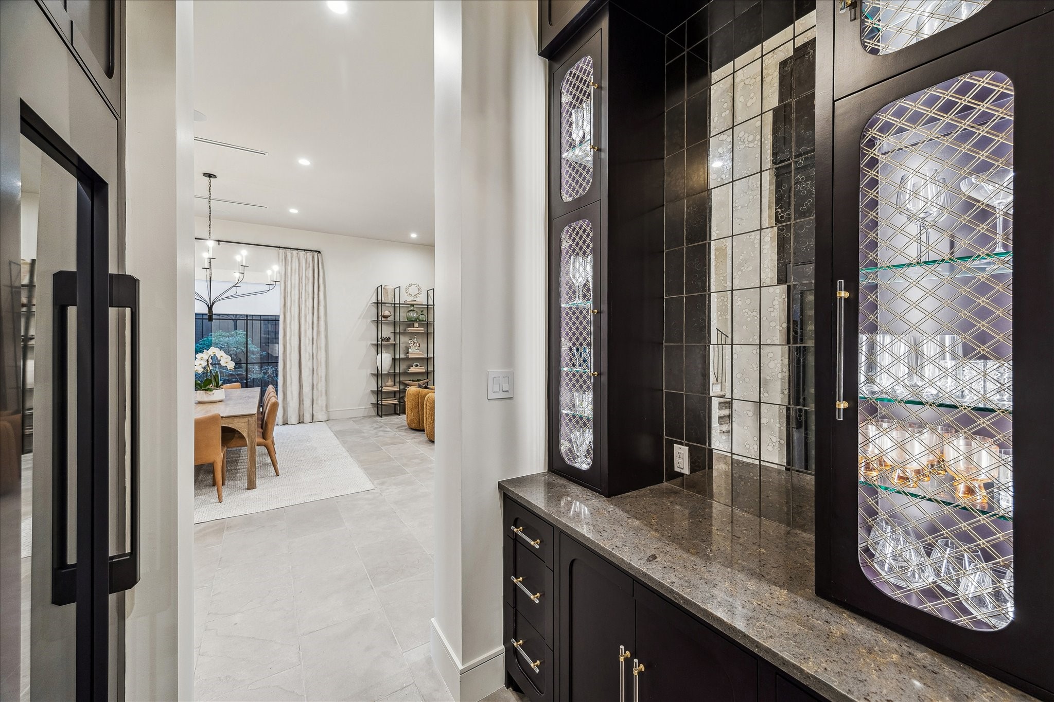3807 Westerman Street Houston, TX 77005 - Photo 18 of 50 An antique mirrored backsplash, Dacor wine refrigerator, and acrylic hardware with custom brass-inset cabinetry define this elegant bar and wine area. A designer chandelier adds a touch of sophistication, with convenient access to the kitchen, dining room, and living room.