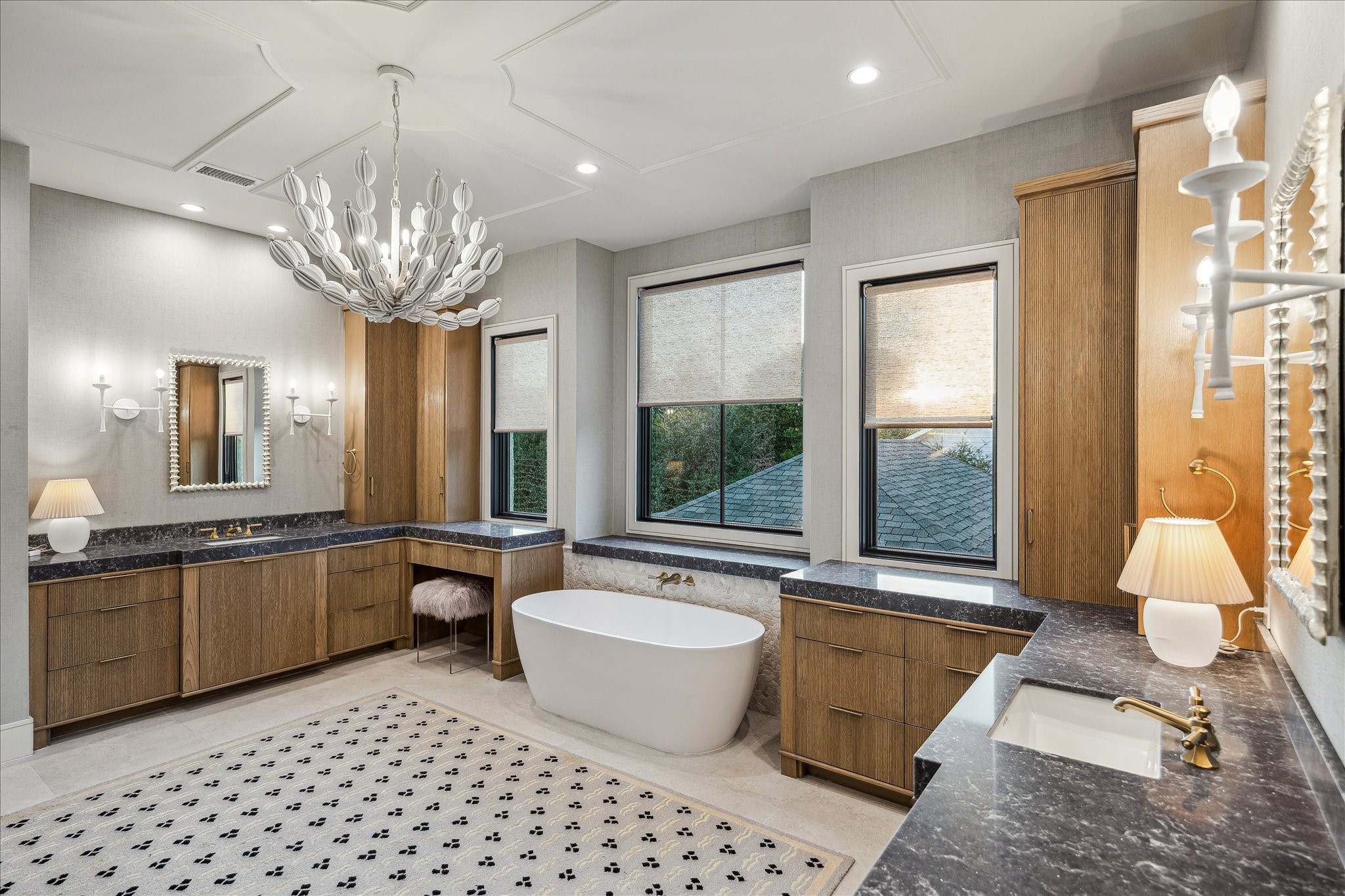 3807 Westerman Street Houston, TX 77005 - Photo 29 of 50 The primary bath showcases a custom accent ceiling design and windows with western exposure that bathe the space in natural light. A luxurious soaking tub and walk-in shower with a seamless glass door and built-in niche create a serene spa experience. Fluted oak cabinetry with brass hardware, double vanities, and white undermount ceramic sinks complete this elegantly designed room.