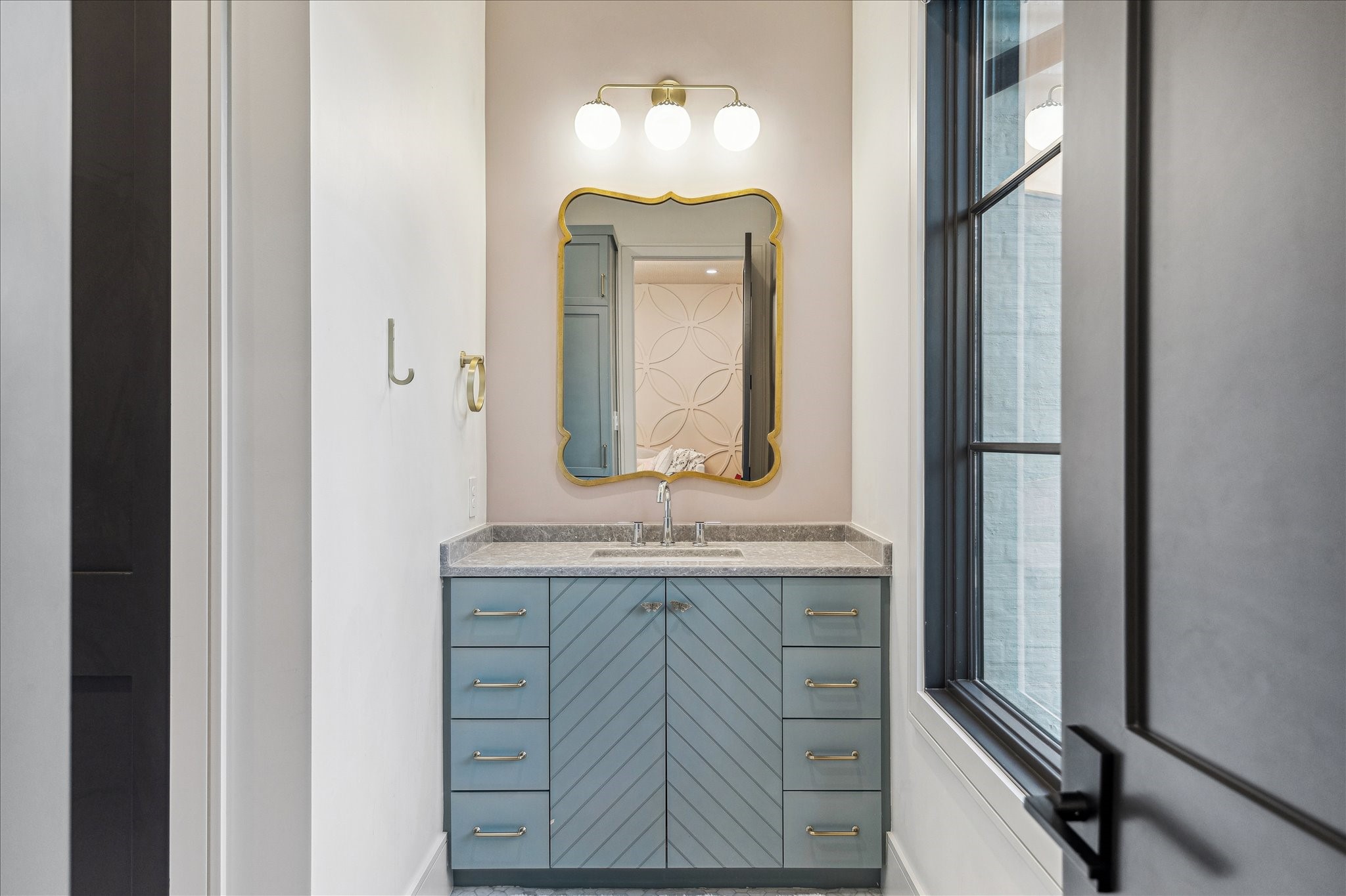 3807 Westerman Street Houston, TX 77005 - Photo 35 of 50 Guest Bathroom 2 features neutral designer wall paint and custom hexagonal tile flooring. A vanity with white undermount ceramic sink, Delta faucet, and storage cabinets below is complemented by designer lighting and a brass-framed mirror. A stylish commode completes the space with a cohesive, elegant design.