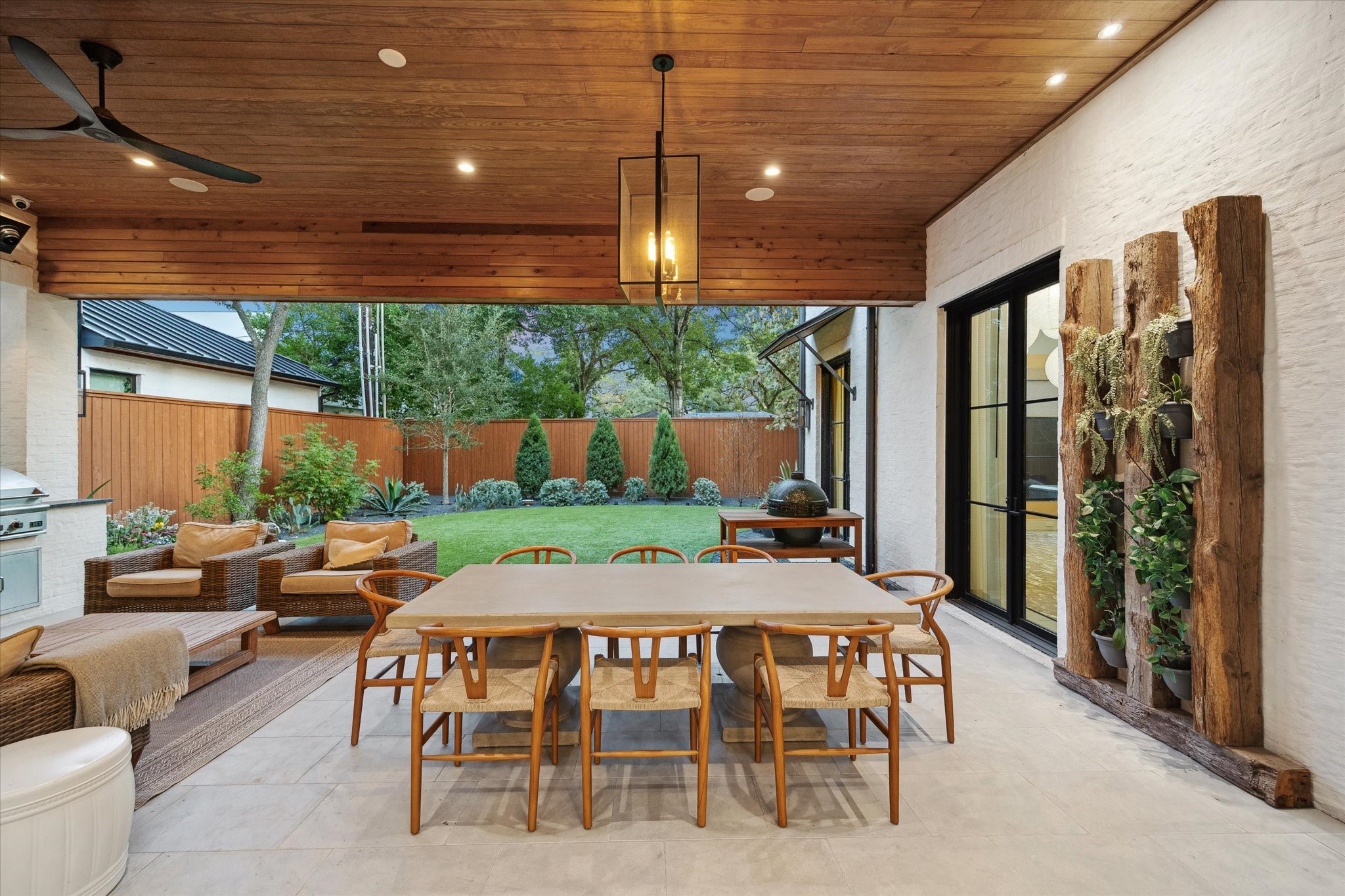 3807 Westerman Street Houston, TX 77005 - Photo 46 of 50 Designed for both relaxation and entertaining, the covered patio features a gas fireplace with brick surround, outdoor kitchen, and timeless Bevolo lantern lighting. Paneled ceiling details, chandelier accents, and built-in heaters enhance the ambiance, blending warmth, luxury, and functionality in perfect harmony.