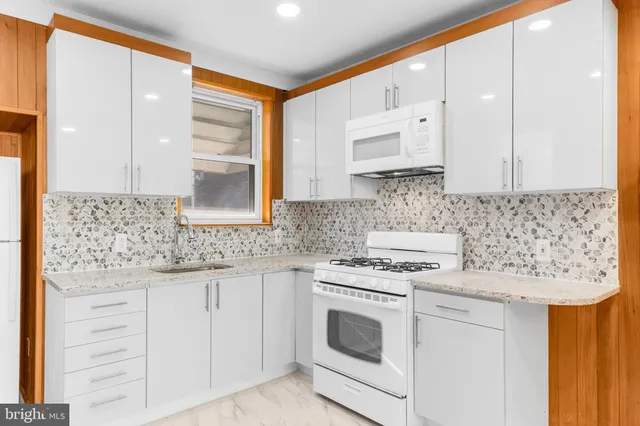 a kitchen with granite countertop white cabinets and white appliances
